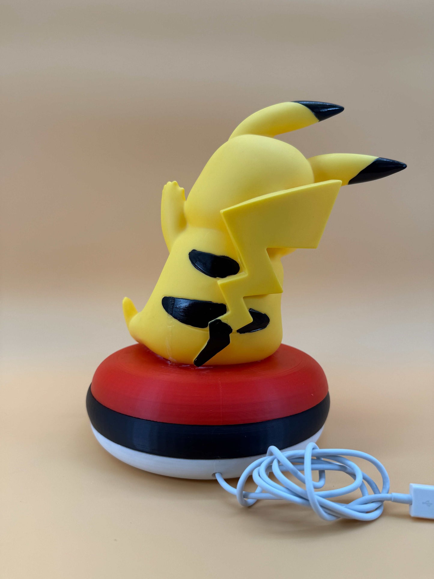 Pikachu Pokeball Desk Lamp with USB cord on beige background.