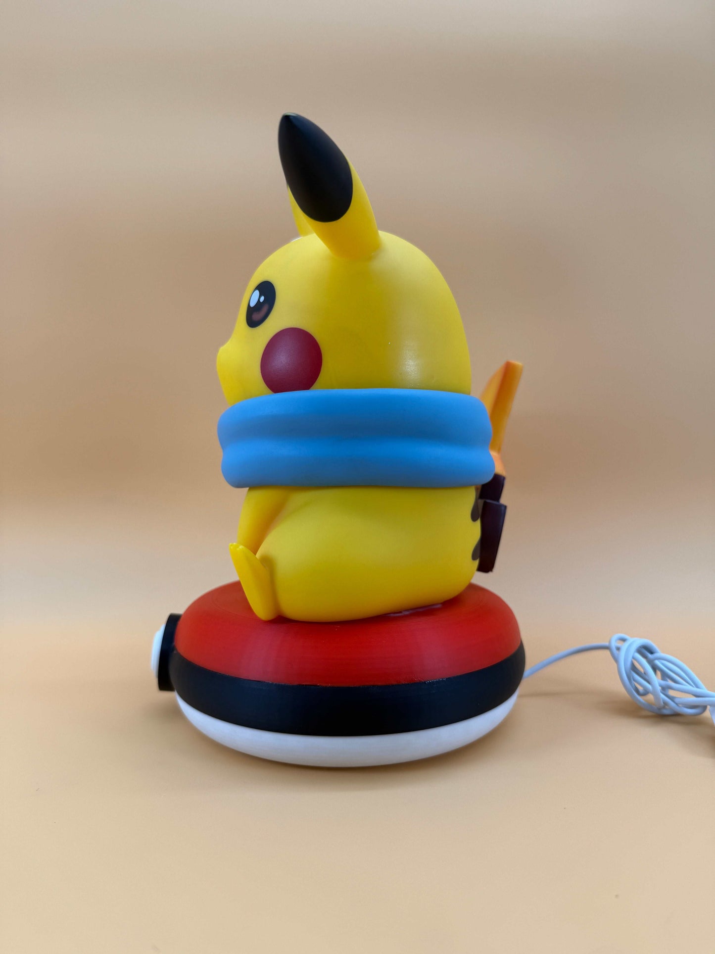 Winter Pikachu Pokeball statue USB desk lamp with a blue scarf, sitting on a Pokeball base.