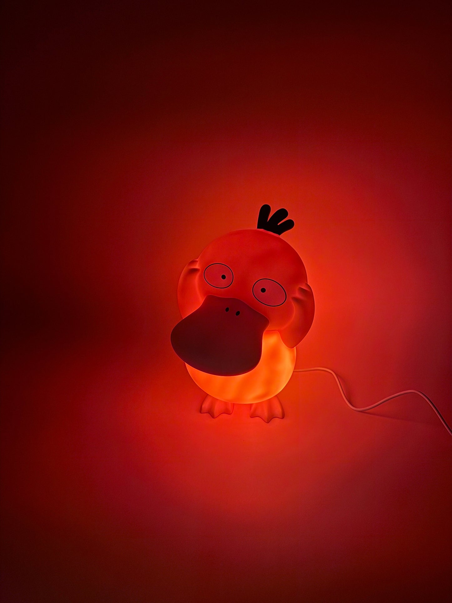 8" Psyduck Statue USB Desk Lamp emitting warm glow in dark room.