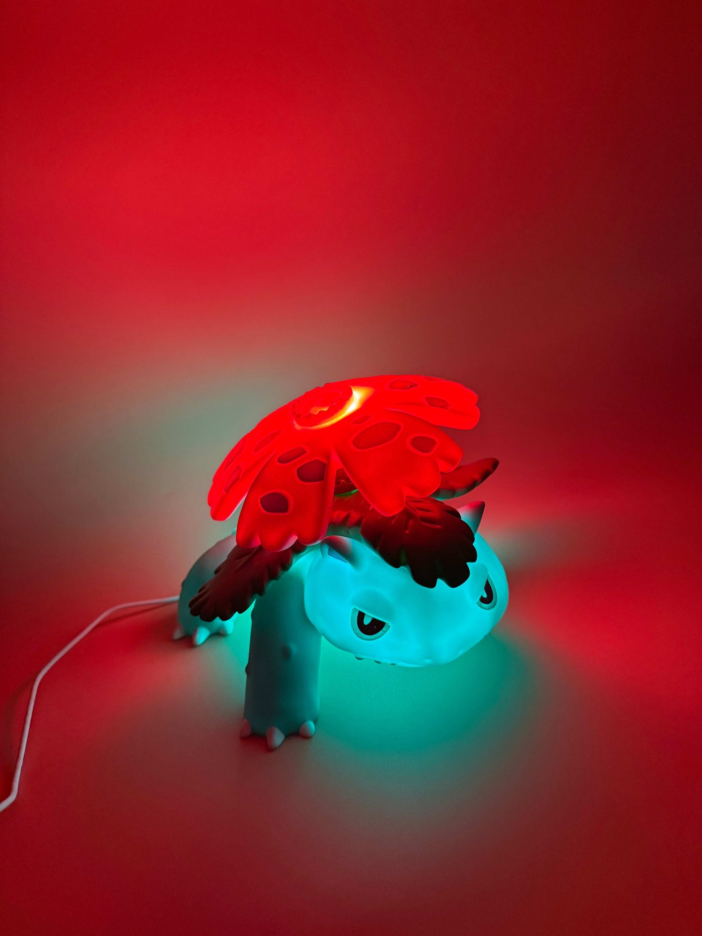 5" x 7" Venusaur Statue USB Desk Lamp with glowing red flower and built-in cord, illuminated against a red backdrop.