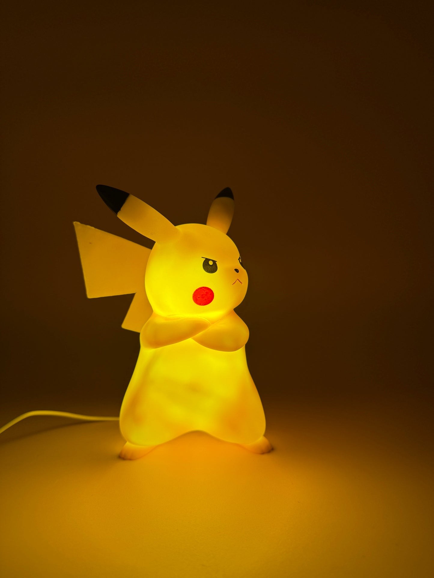 7" Angry Pikachu Statue USB Desk Lamp in a dark setting, glowing warmly.
