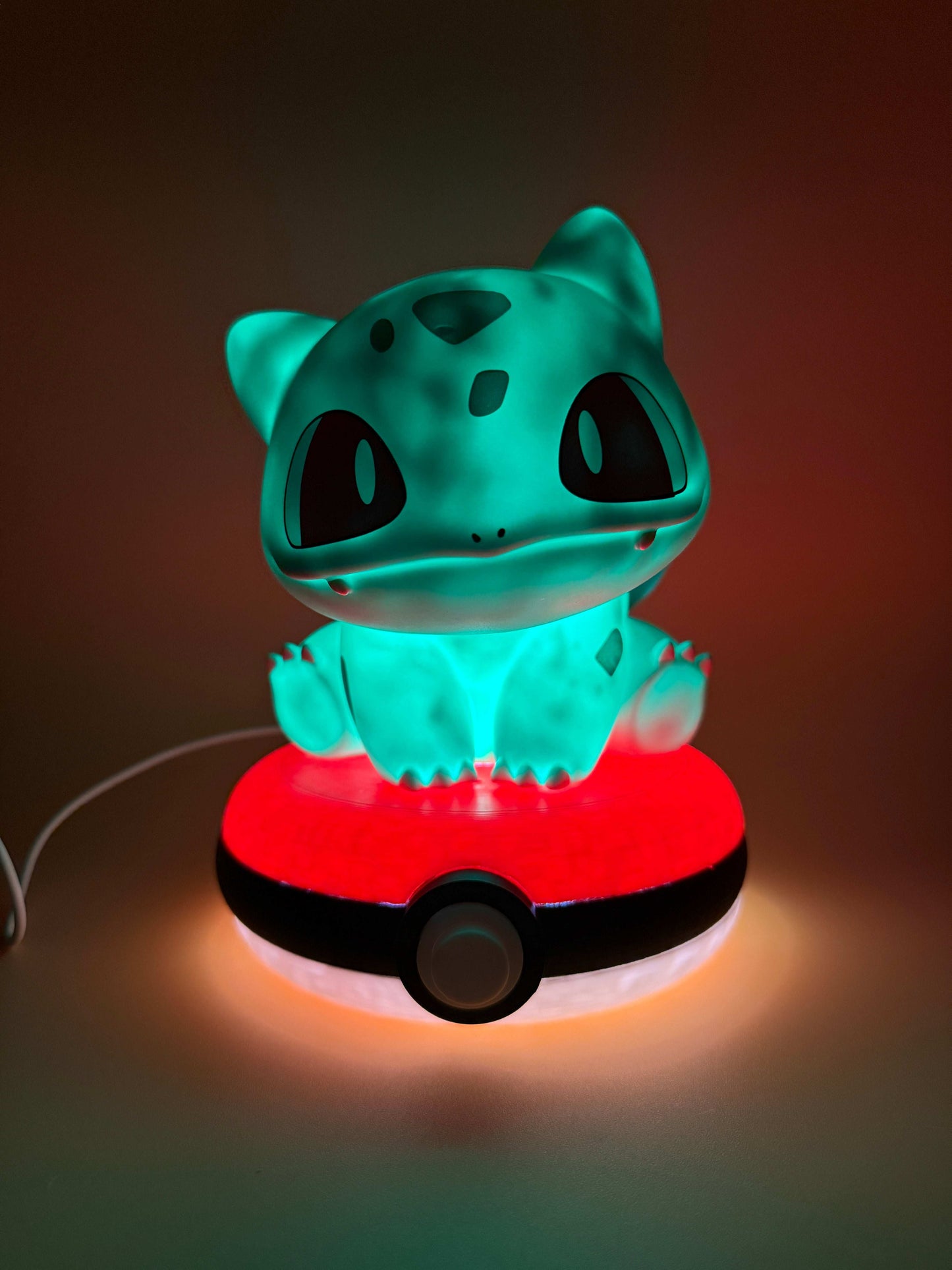 Bulbasaur Pokeball desk lamp with USB cord, glowing on a dark background.