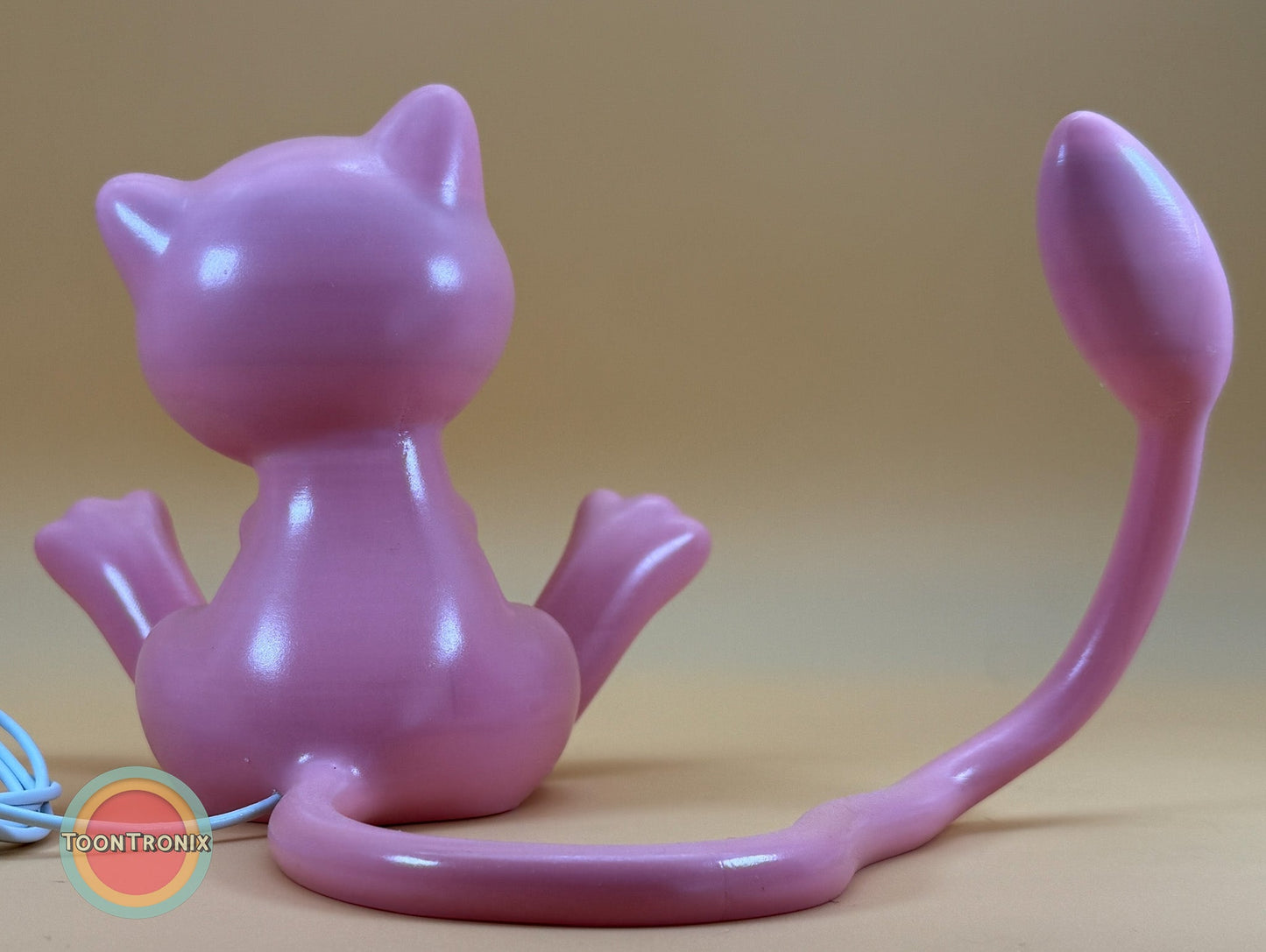 pink 6 inch tall 11 inch wide Mew Pokemon statue USB desk lamp with long tail and built-in USB cord on beige background