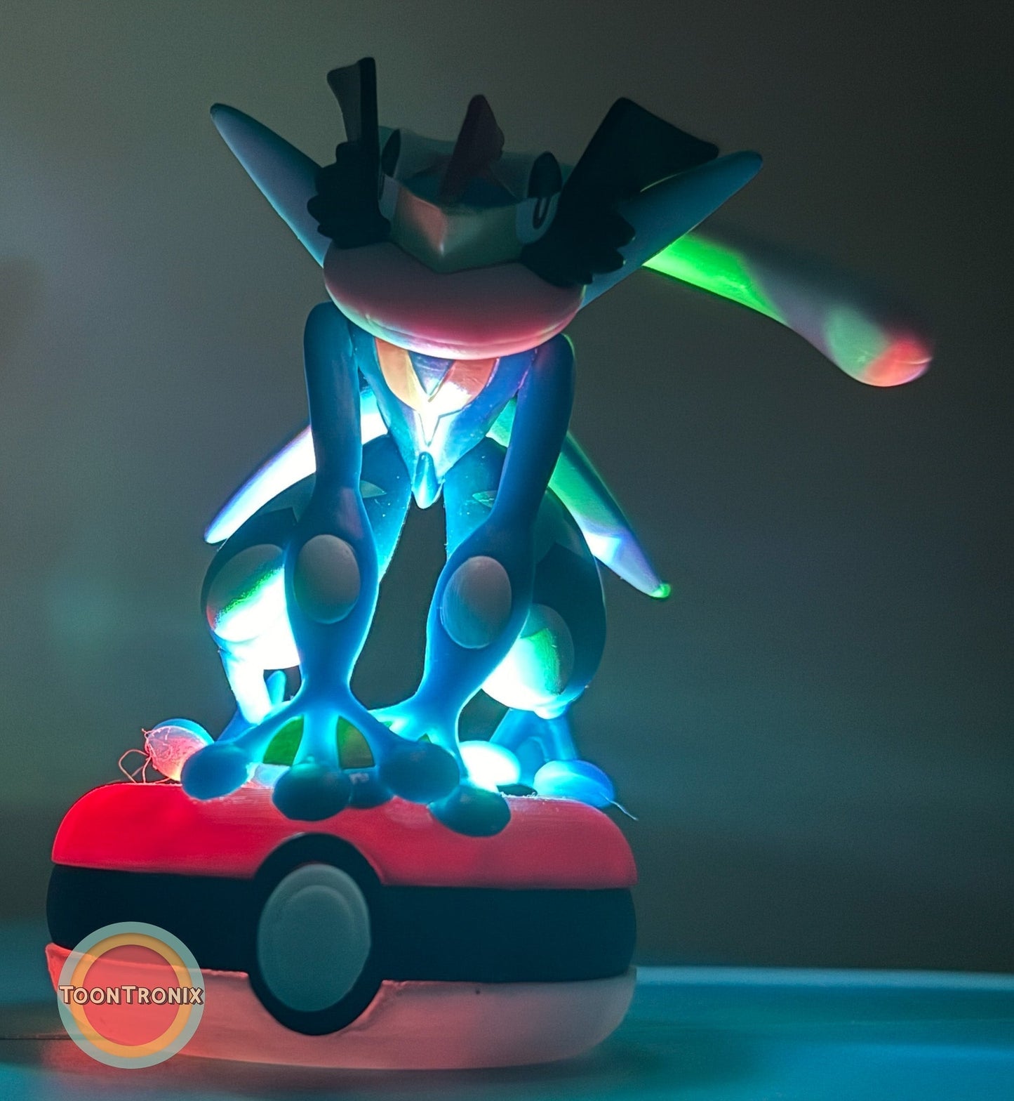 3" Greninja Pokémon statue USB desk lamp glowing with colorful light sitting on a Poké Ball base