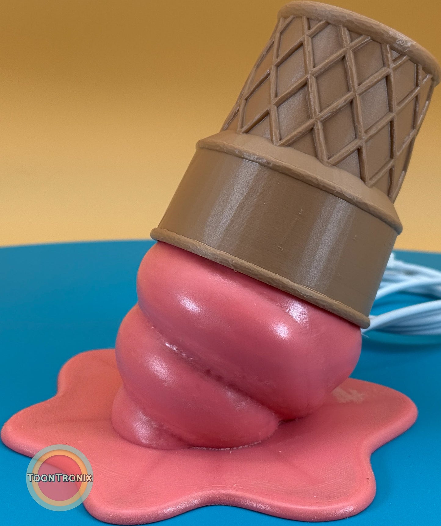 Pink ice cream cone desk lamp with wood finish and built-in USB cord on blue surface