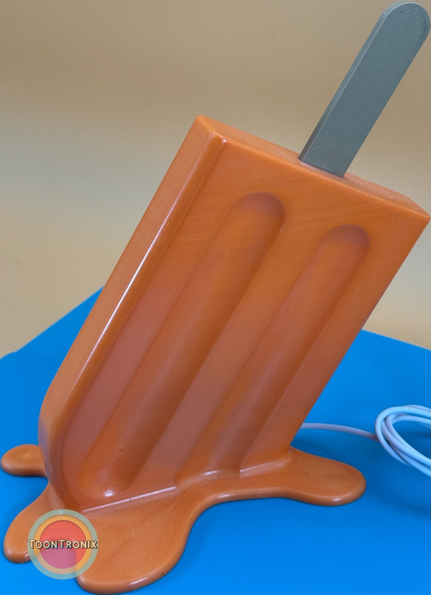 6 inch orange popsicle desk lamp with USB cord on blue surface