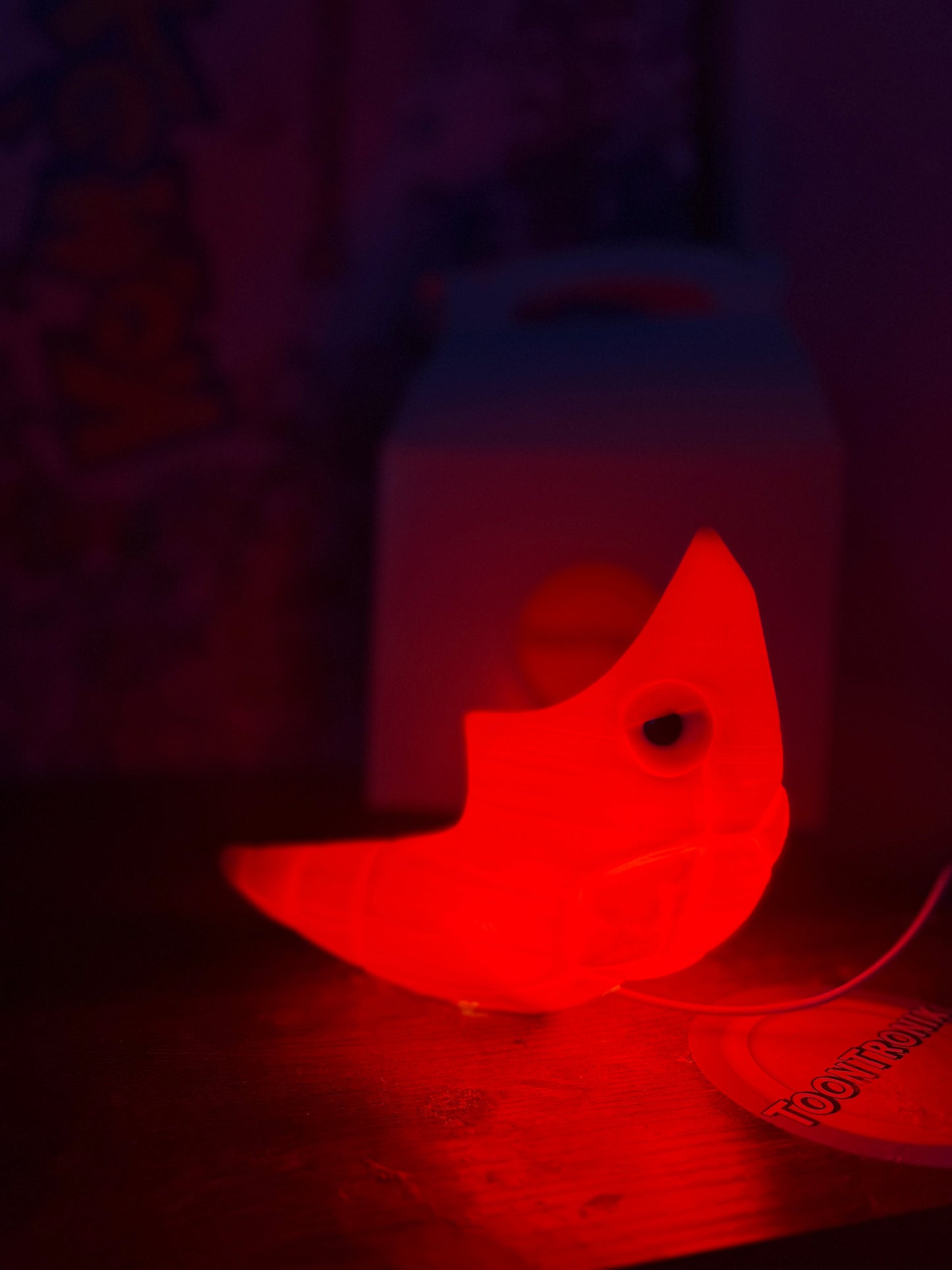 6" Shiny Metapod LED desk lamp with USB cord and woodified finish glowing red in dark room