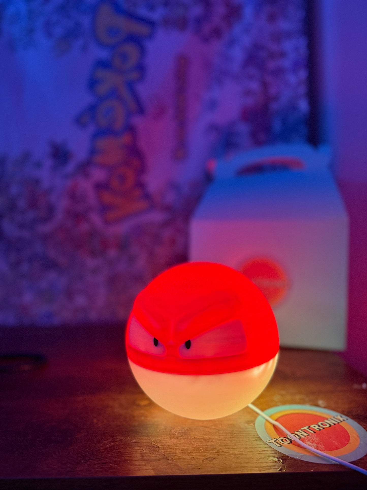 6" Voltorb Pokemon statue desk lamp glowing red and white with USB cord on wooden surface