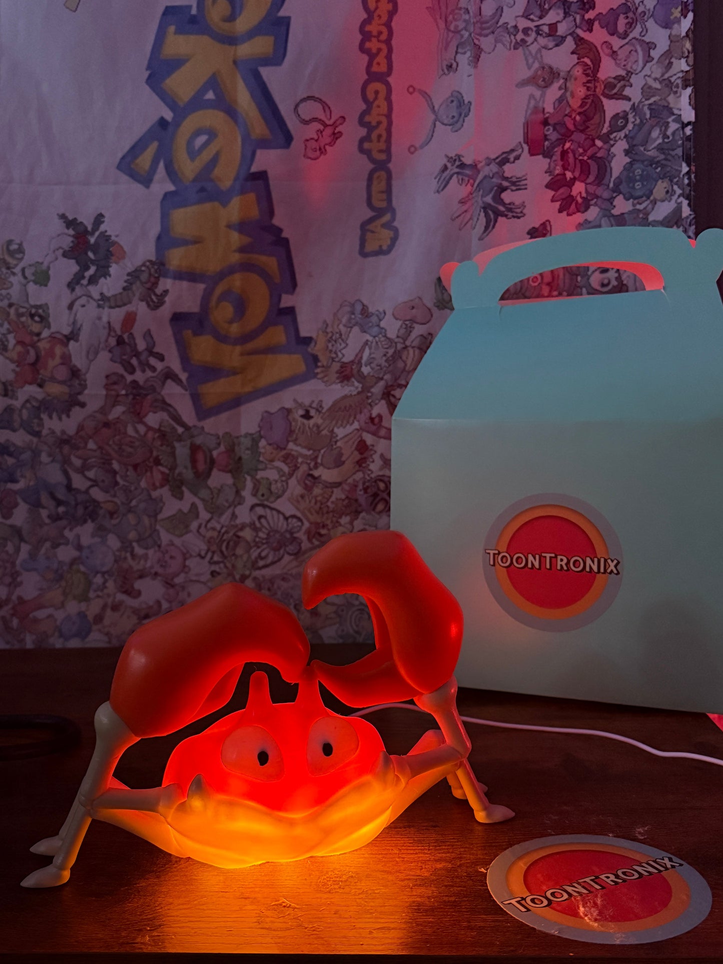 6" Krabby Pokemon desk lamp with USB cord and wood-like finish lit on a desk with Pokemon backdrop