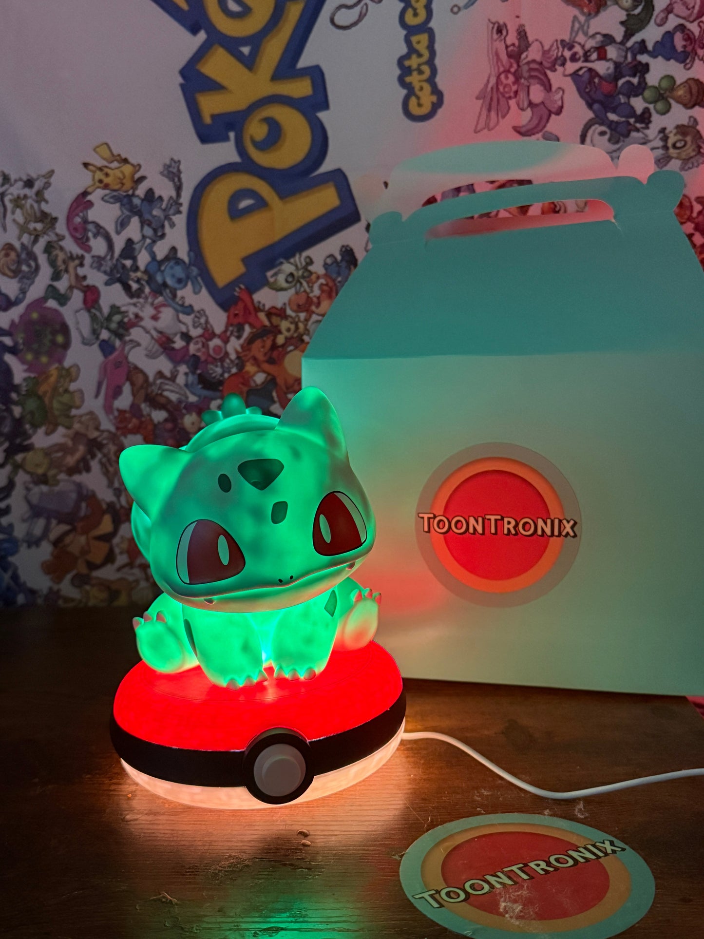7-inch Bulbasaur Pokeball desk lamp with LED light and built-in USB cord, glowing green figurine on a red and white Pokeball base.