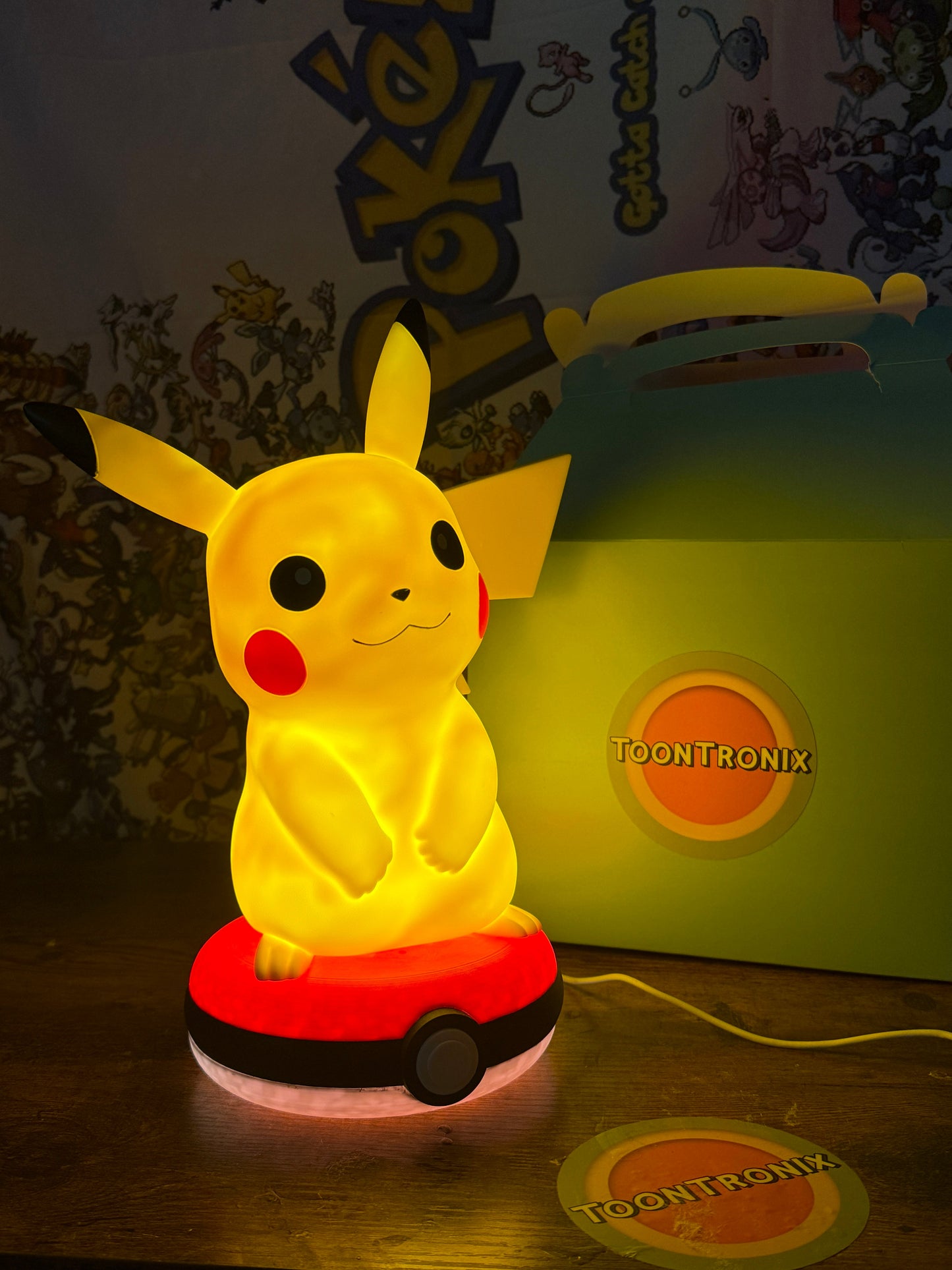 12” Pikachu Pokeball USB LED desk lamp illuminated on wooden surface with Toontronix branding background