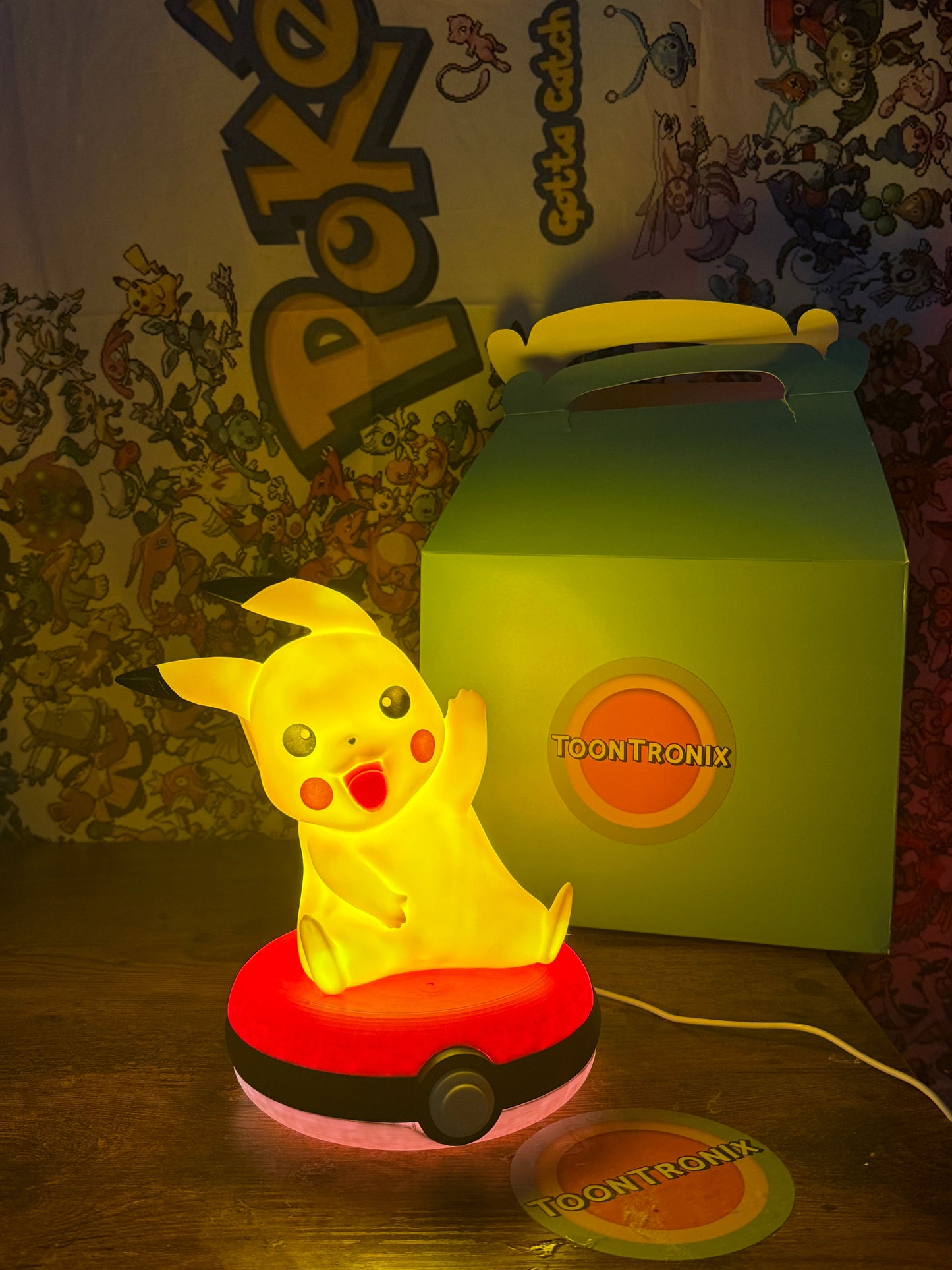 Pikachu Pokeball desk lamp with LED light and built-in USB cord glowing on wooden surface