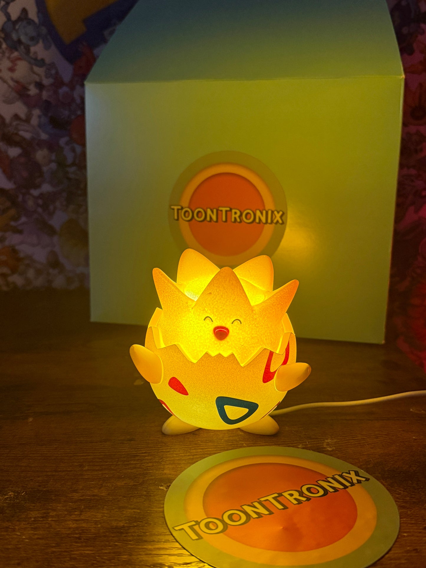 Togepi Desk Lamp glowing with built-in USB cord on a wooden surface with Toontronix branding in the background and foreground