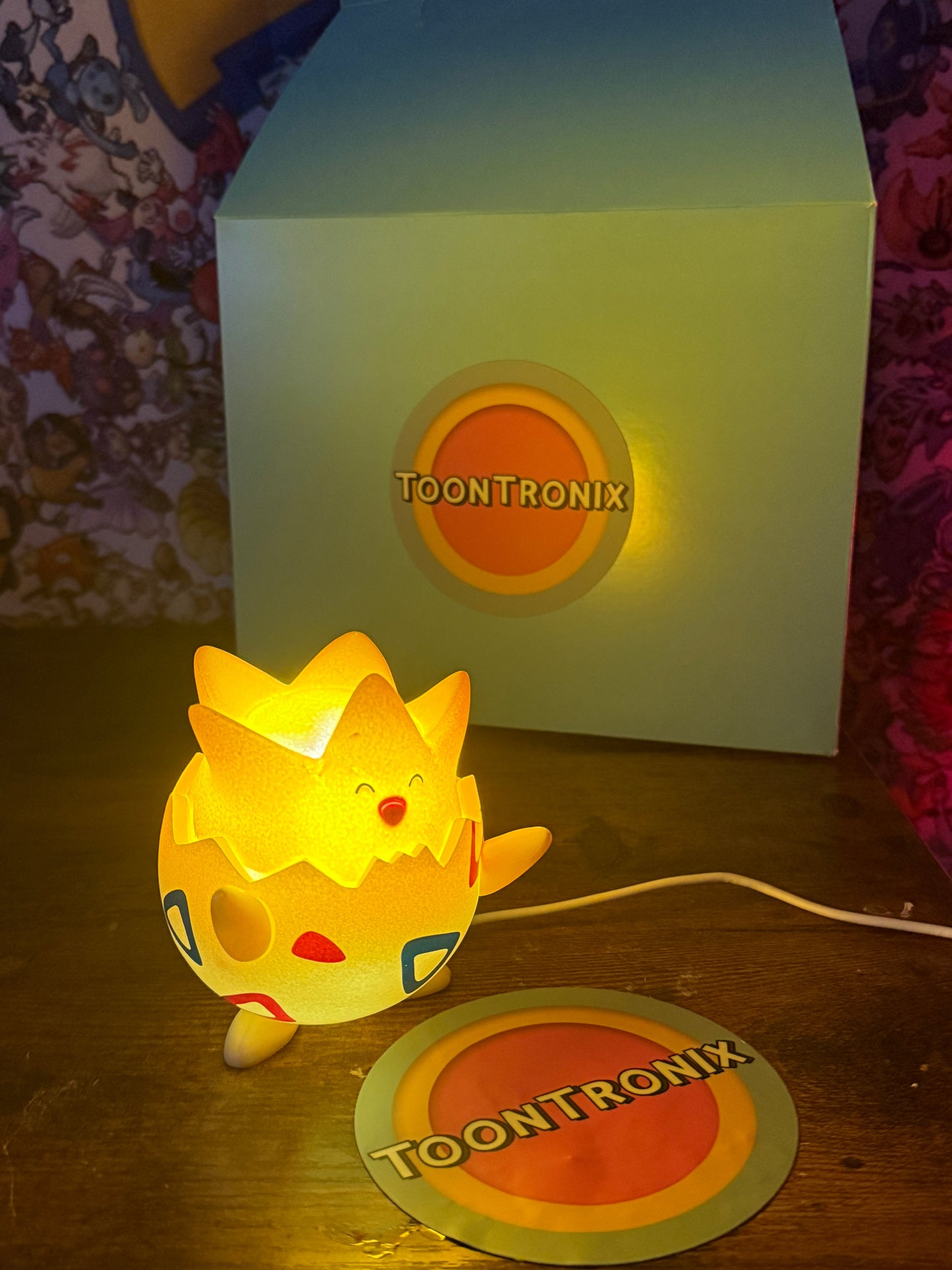 3.5-inch Togepi desk lamp toy figure with built-in USB cord glowing warmly beside Toontronix packaging and coaster