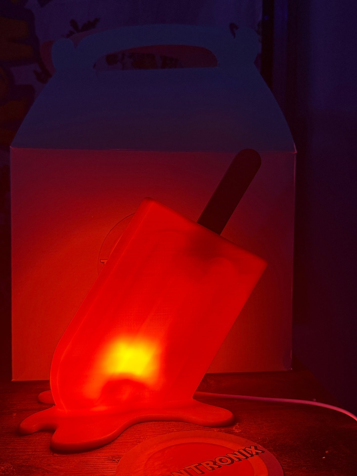 6-inch red popsicle-shaped LED desk lamp with built-in USB cord glowing on dark surface