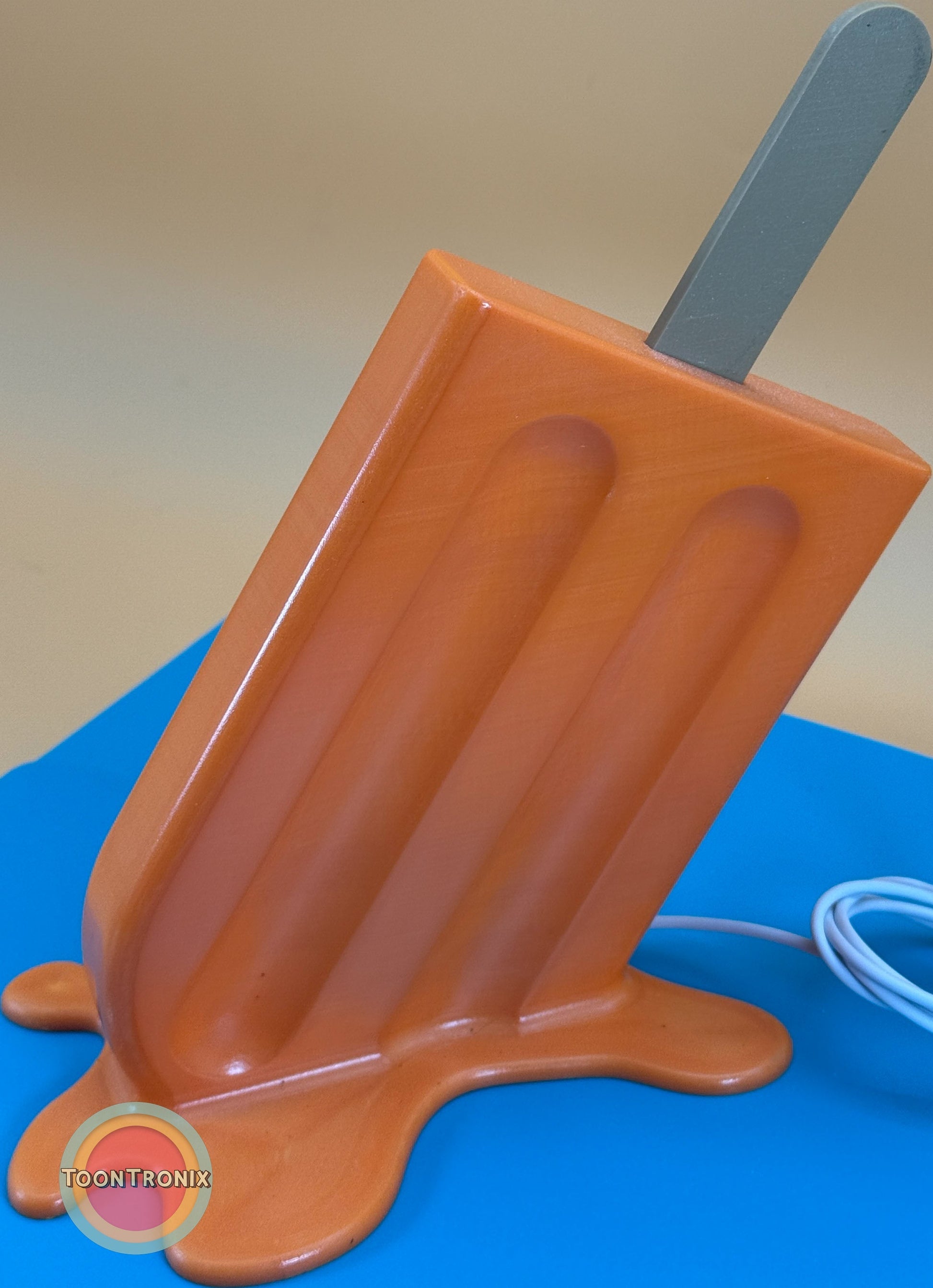 6 inch orange popsicle desk lamp with USB cord on blue surface