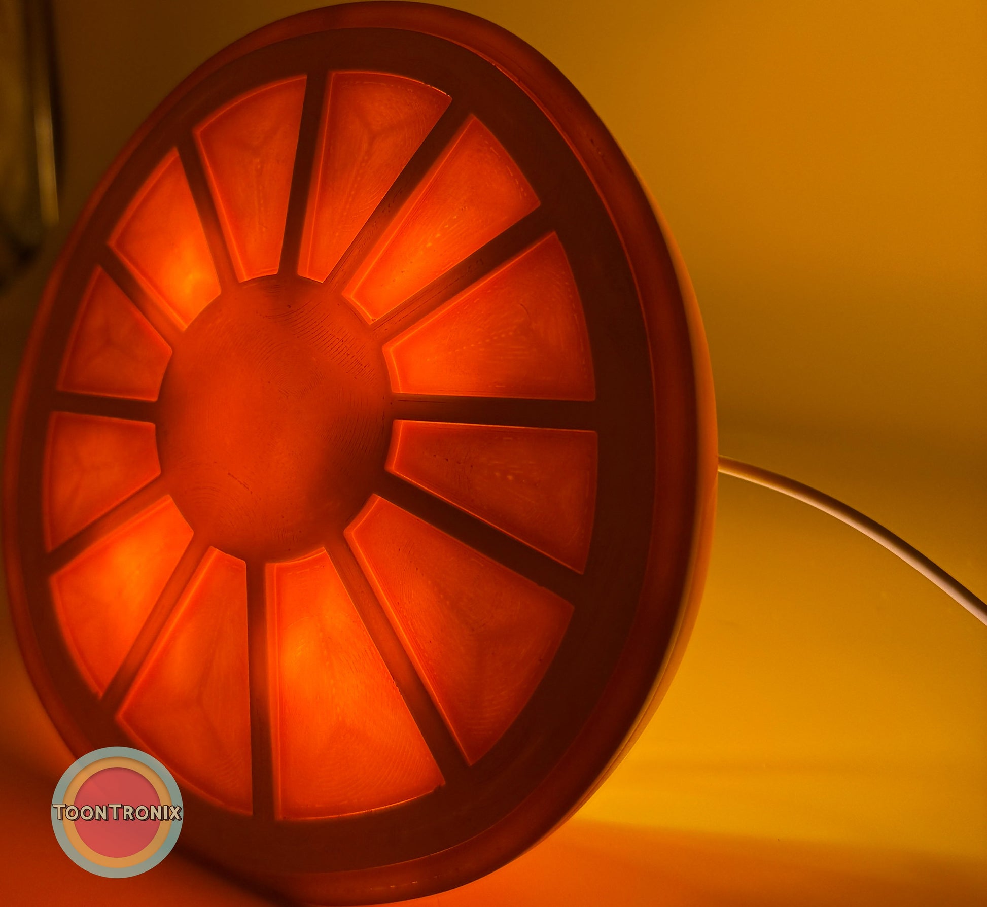 Glowing orange citrus slice shaped desk food lamp with built-in USB cord on warm background