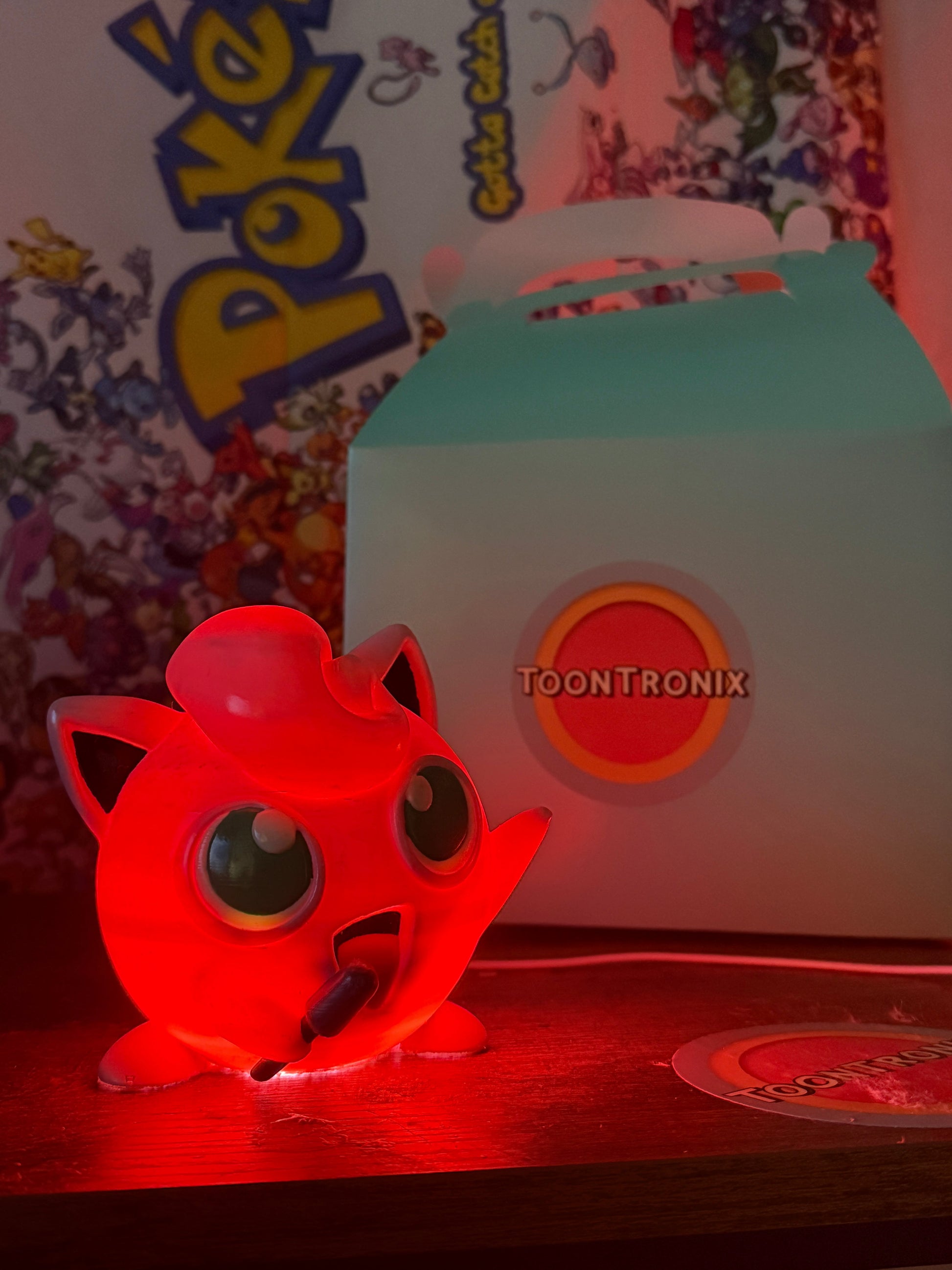 Red glowing 4.6" Jigglypuff Pokemon desk lamp with USB, wooden texture finish, and Pokemon backdrop.