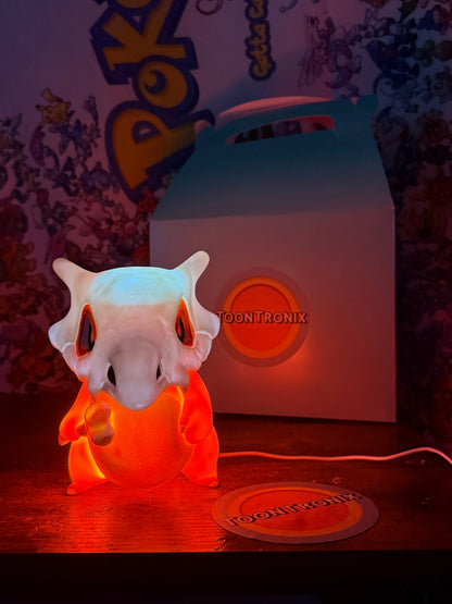 6" Cubone desk lamp glowing orange with built-in USB cord and Toontronix packaging in background