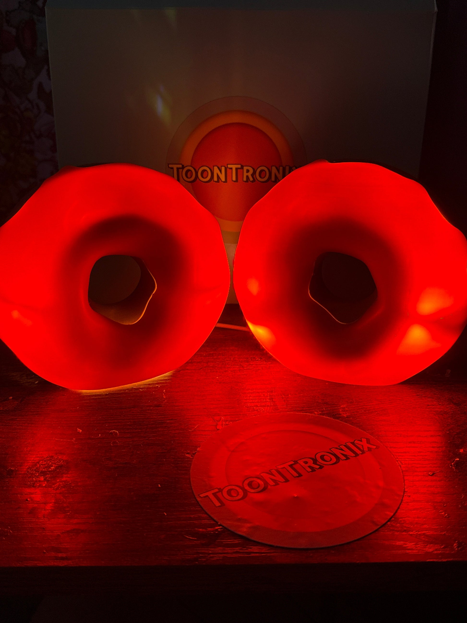 Red glowing donut desk lamps with built-in USB cords on wooden surface