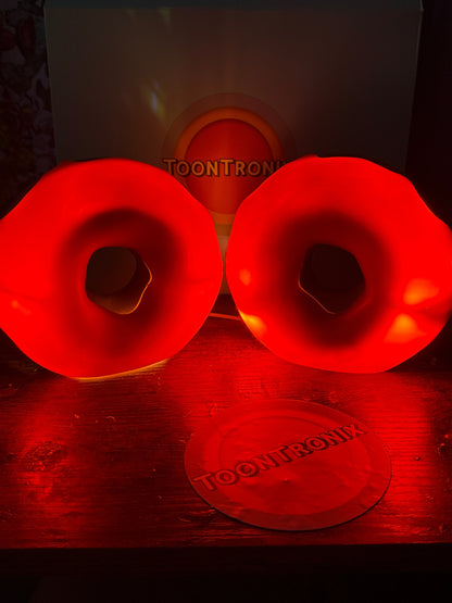 Red glowing donut desk lamps with built-in USB cords on wooden surface